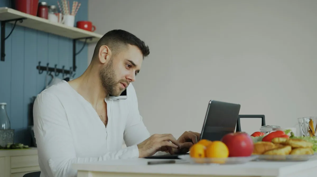 Man working on a laptop at a kitchen table