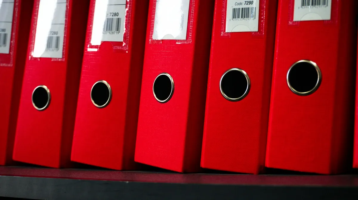 Row of red labeled binders on an office shelf